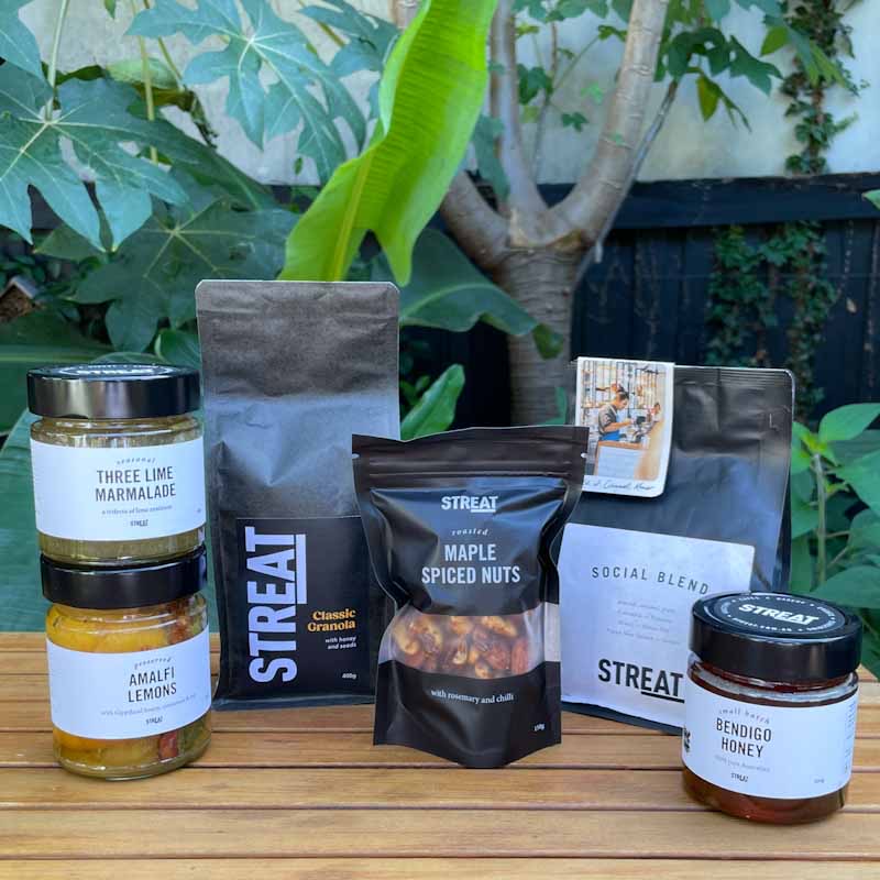 STREAT's festive Christmas hampers taste good, and do good, too. Featuring a white background with products lined up – Christmas puddings, nougat, festive granola, jam, coffee and ginger bread stars.